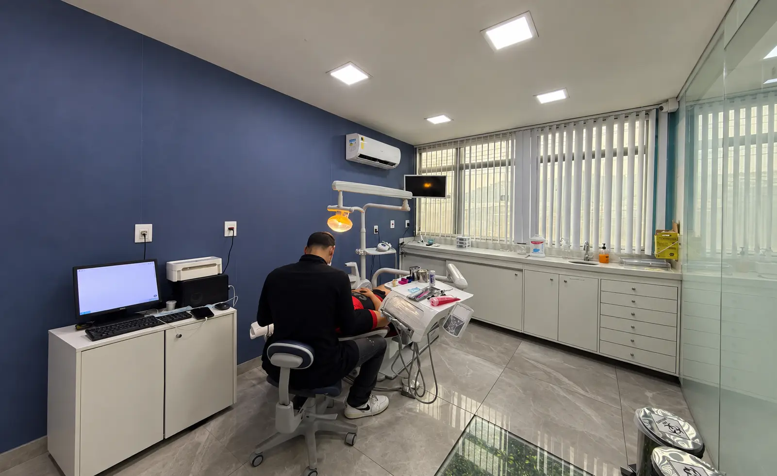 Consultório iluminado com cadeira odontológica e parede decorada