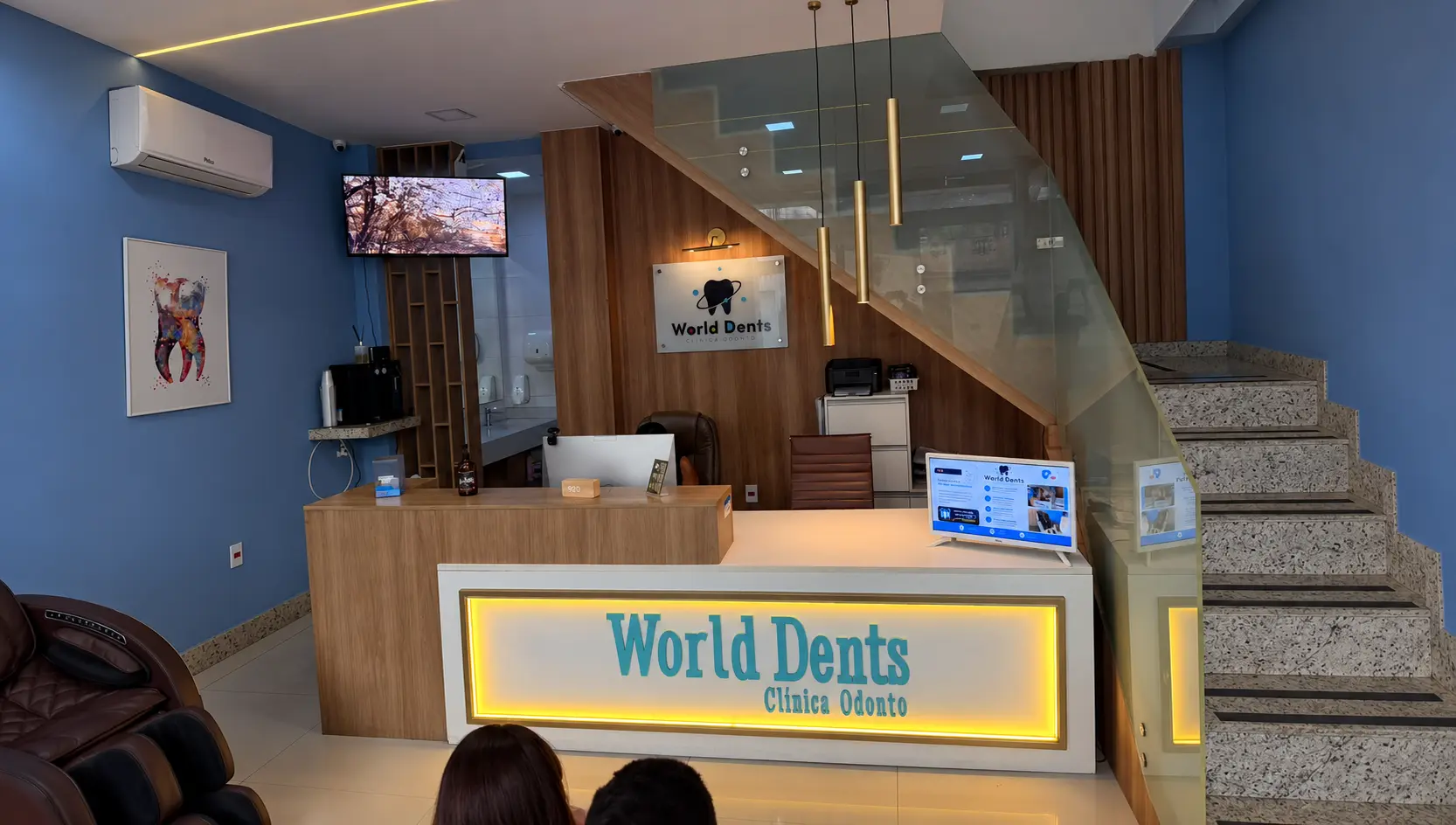 Recepção da World Dents com balcão iluminado, madeira e paredes verde-água